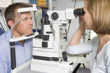 Optometrist in exam room with man Stock Photo