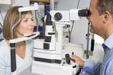 Optometrist in exam room with woman in chair Stock Image