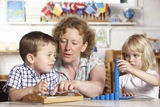 Adult Helping Two Young Children at Montessori/Pr Stock Images