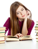 Young girl sitting at the desk and reading book. Royalty Free Stock Photo
