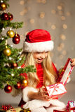 Miss santa opening a gift Royalty Free Stock Photography