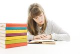 Young girl sitting at the desk and reading book. Stock Images