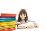 Young girl sitting at the desk and reading book. Stock Images