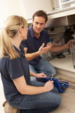 Plumber Teaching Apprentice To Fix Kitchen Sink Stock Photo