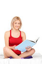 Young smiling woman reading a book on a bed Stock Photography
