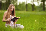 Student girl sit on lawn and reads textbook. Royalty Free Stock Image