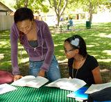 Two black teens study their books at the park Stock Images