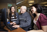 Volunteers teaching a senior how to use a computer Royalty Free Stock Images