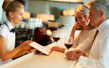Female barmaid taking order from senior couple Stock Image