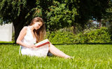 Student sit on lawn and reads textbook Stock Photo