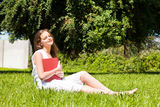 Student sit on lawn and reads textbook Royalty Free Stock Photo