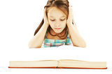 Young girl sitting at the desk and reading book Stock Images