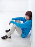 Teenager sitting by the wall Stock Photography