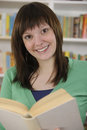 Young woman reading a book in library Royalty Free Stock Image