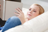 Young girl reads the book lying on the sofa Royalty Free Stock Photography