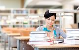 Young female studies with piles of books Royalty Free Stock Image