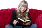 Young girl on red sofa read a book Stock Photos
