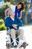 Adult Daughter Pushing Senior Father In Wheelchair Stock Photo