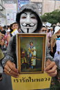 Anti government white mask protest in bangkok an protester wearing a guy fawkes and holding a portrait of the current thai king Royalty Free Stock Photography