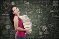Beautiful female student bring stack of books in class happy and the Royalty Free Stock Photo