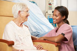 Nurse Talking To Senior Female Patient Seated In Chair Stock Image