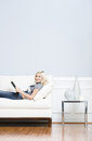 Young Woman Lying on Sofa Reading Book Stock Photos